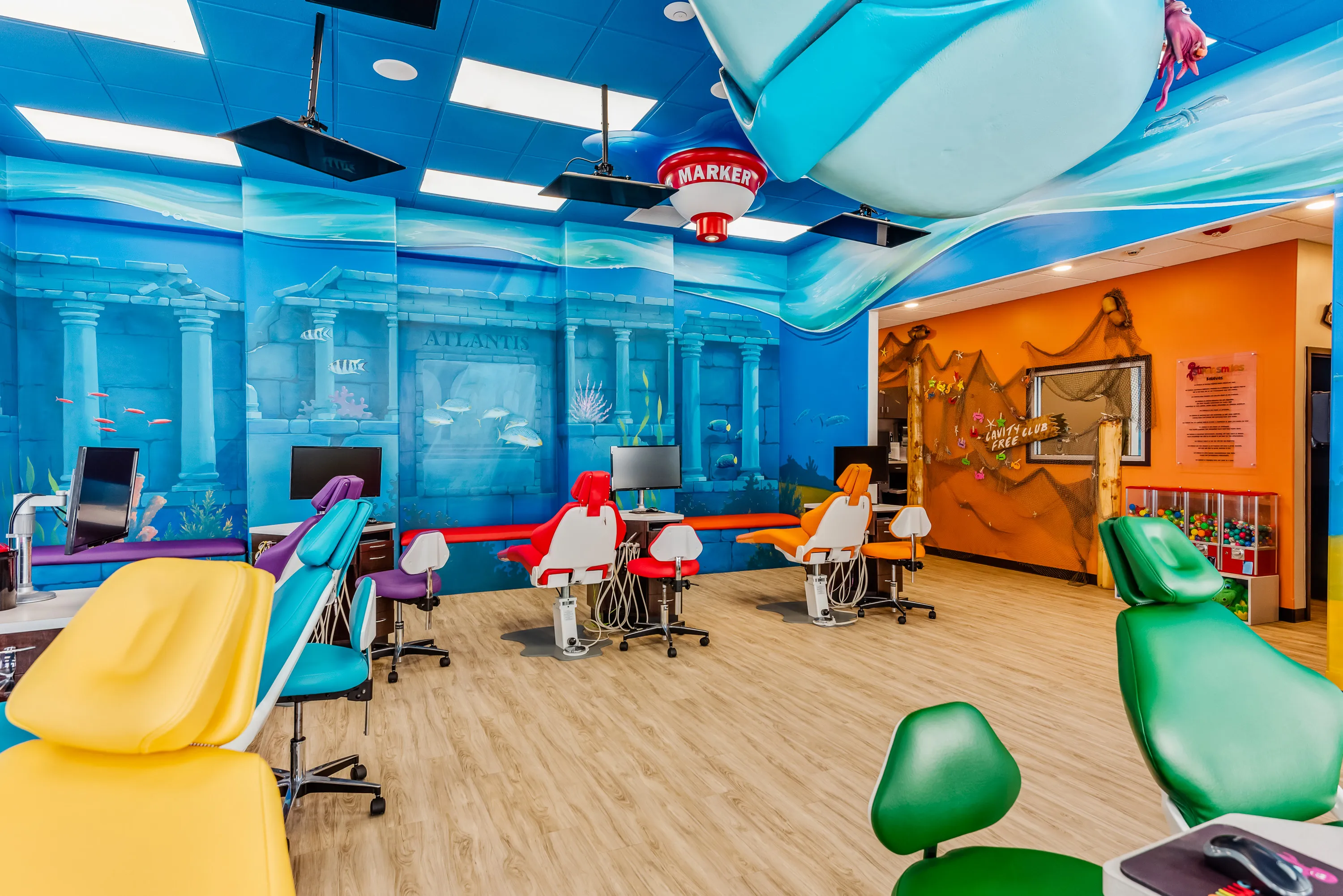 A Super Smiles treatment room with an undersea mural, treatment chair, and the Cavity Free Club wall visible through the doorway